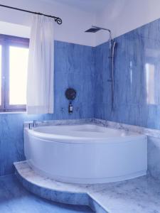 a large white tub in a blue bathroom with a window at Hotel I Portici in Arezzo