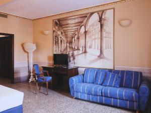 a living room with a blue couch and a desk at Hotel I Portici in Arezzo