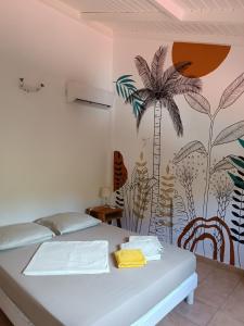 a bedroom with a bed with a palm tree mural at GîteTi Coco de Malendure - Bord de mer - 4 pers in Bouillante +41 photos