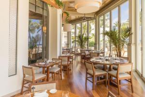 a restaurant with tables and chairs and windows at Eau Resort & Spa in South Palm Beach