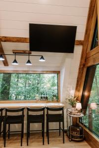 a kitchen with a bar with black chairs and a large window at Wilewood A-Frame, Romantic Treehouse Getaway, Hot Tub in Abbeville
