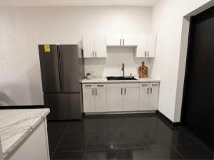a kitchen with white cabinets and a black refrigerator at TinyHouseMX1 Comodidad y playa que se disfruta in San Patricio Melaque +6 photos