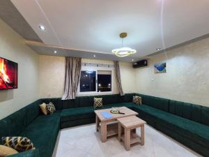 a living room with a green couch and a table at Appartements meublés avec vue sur la mer dans la ville jebha T1 in Yebha