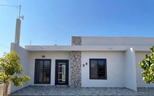 a white house with black doors and windows at TinyHouseMX1 Comodidad y playa que se disfruta in San Patricio Melaque