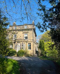 an old stone house with trees in front of it at The Spa Town Loft in Buxton
