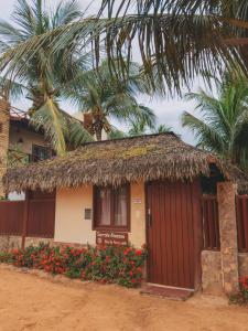 a small house with a thatched roof and a palm tree at Serrote Breezes Apartamento 04 in Jericoacoara