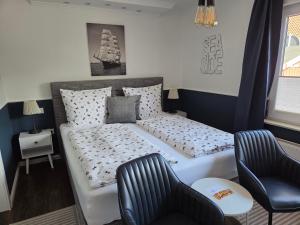 a bedroom with a large bed and two chairs at Pension Zur Brandung in Büsum