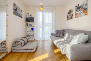 a living room with a gray couch and a wooden floor at Pino Home in Neringa