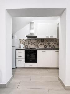 a kitchen with white cabinets and a stove at Casa Berso' a Marina di Cecina by Zoom In Earth in Marina di Cecina