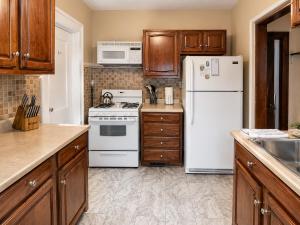 a kitchen with white appliances and wooden cabinets at Spacious Frontier Park Apartment in Erie