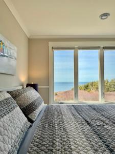 a bedroom with a large bed and large windows at Oceanfront Escape on the Cabot Trail by Cabotopia in Chéticamp