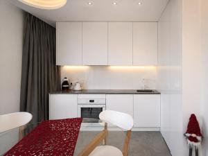 a kitchen with white cabinets and a table and chairs at Kryształ Górski apartament z sauną in Szczyrk