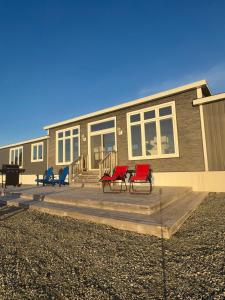 two red chairs on a deck in front of a house at Oceanfront Escape on the Cabot Trail by Cabotopia in Chéticamp