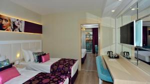 a hotel room with two beds and a desk at Azura Deluxe Resort & Spa - Ultra All Inclusive in Avsallar