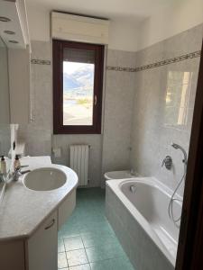 a bathroom with two sinks and a tub and a window at Un sogno tra lago e monti in Pescate