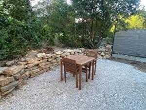 a wooden table and chairs in front of a stone wall at L'échappée in Viols-le-Fort