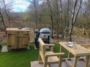 a grill and a table and chairs on a lawn at Green woodland bell tent in Ynys Station