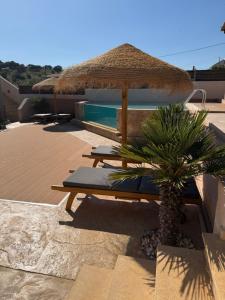 a table with a straw umbrella next to a pool at Jimmy's place in Artemida