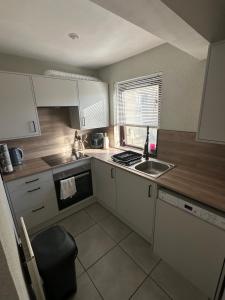 a small kitchen with white cabinets and a sink at Impala Apartment in Wick