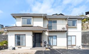 a white house with a balcony at Ninja Village - Miyajima in Hatsukaichi