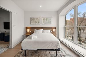 a white bedroom with a large bed and a window at Le Nomade Quartier Chinois in Montreal