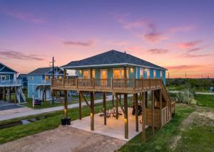a house with a wrap around deck at sunset at BeachQuest Beachfront in Bolivar Peninsula