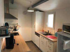 a kitchen with white cabinets and a sink and a window at hirondelle 1 in Noirmoutier-en-l'lle