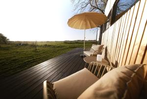 a wooden deck with chairs and an umbrella at NOAH Cabin No2 - An wunderschöner Windmühle in Beverstedt