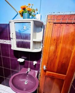 a bathroom with a sink and a tv on the wall at Hostal El Viajero-Mindo in Mindo