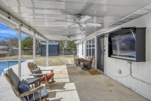 a screened porch with chairs and a flat screen tv at Relaxed Poolside Gym Escape in Green Cove Springs