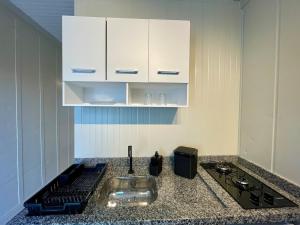 a kitchen counter with a sink and white cabinets at 12 · Studio 22 Itajaí microcasa in Itajaí +11 photos