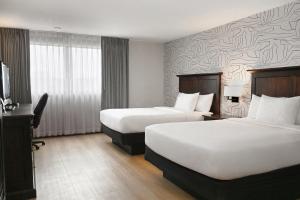 a hotel room with two beds and a desk at Clifton Victoria Inn at the Falls in Niagara Falls +18 photos