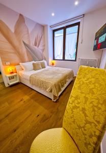 a bedroom with a bed and a yellow chair at NS Urban Suite in Udine