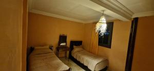 a bedroom with two beds and a chandelier at Villa Galactik Pegasus in Tamraght Ou Fella