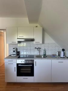 a kitchen with white cabinets and a sink at LORENZ Apartment 2 in Hattingen