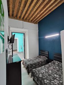 a room with two beds and a desk with a tv at Casona Poblana Hotel Puebla in Puebla