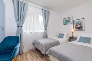 a bedroom with two beds and a chair and a window at Apartments Mare in Punat +64 photos