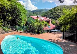 a person swimming in a pool in front of a house at GîteTi Coco de Malendure - Bord de mer - 4 pers in Bouillante