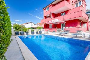 a swimming pool in front of a building with a red building at Apartments Mare in Punat