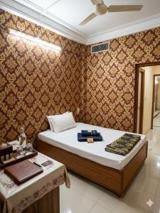 a bedroom with a bed and a table in a room at Narmada Gest House in Indore +38 photos