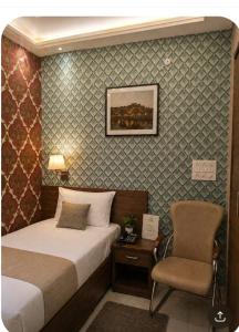 a hotel room with a bed and a chair at Narmada Gest House in Indore