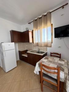 a kitchen with a table and a white refrigerator at Vila Riviera in Ksamil +91 photos