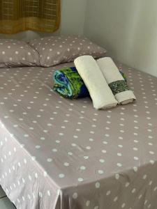 a bed with white polka dot sheets and two towels at Pousada são Martins in Estivado
