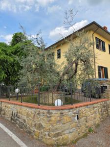 a stone wall in front of a yellow house at Il Piccolo Oliveto in Arezzo