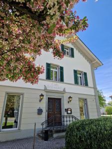 a white house with green shuttered windows at Ferienwohnung am Schlossplatz in Wolfegg