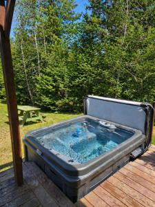a hot tub sitting on top of a wooden deck at SPA private pond and beach volleyball in Lac-Superieur