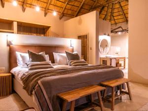 a bedroom with a large bed with two wooden benches at Avenir Safari Group in Okahandja