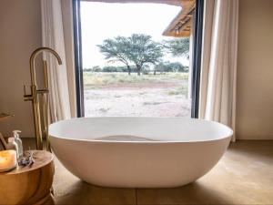 a large white bath tub in a bathroom with a window at Avenir Safari Group in Okahandja +9 photos