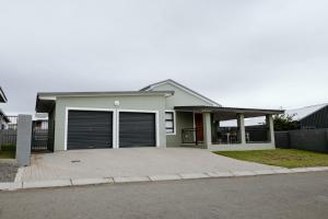 a house with two garage doors and a driveway at Melk en Heuning Uitspan in Orania