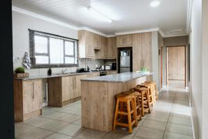 a kitchen with wooden cabinets and a counter with bar stools at Melk en Heuning Uitspan in Orania